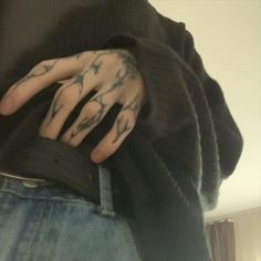 a person with tattoos on their arms and hands is wearing a black shirt while holding onto his jeans