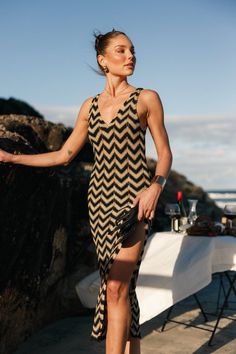 a woman is standing on the beach in a chevron dress and high heeled sandals