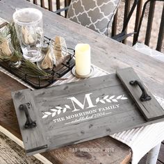 a wooden tray sitting on top of a table next to a candle and some glasses