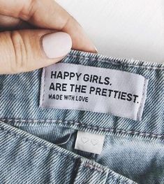 a woman's hand is holding onto the label on her jean pants that says, happy girls are the prettiest made with love