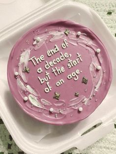 a pink cake with white frosting on top in a plastic container that says the end of a decade, but the start of an age