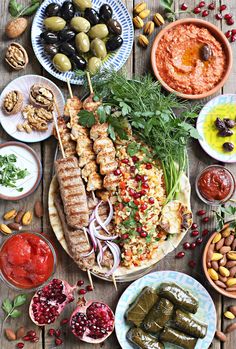 an assortment of food on a wooden table with plates and bowls filled with different foods