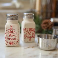 merry christmas salt and pepper shakers sitting on a kitchen counter next to a measuring bowl