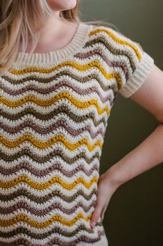 a woman with her hands on her hips wearing a knitted sweater that has wavy stripes