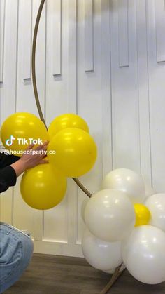 a person sitting on the floor with some balloons in front of them and one balloon attached to a pole