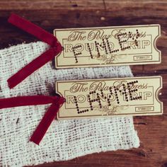 two wooden tickets with red ribbon tied around them