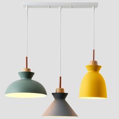 three different colored lights hanging from a ceiling light fixture in various colors and shapes, one yellow, the other green