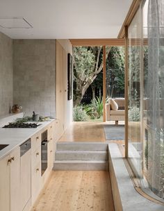 an open kitchen and living room with wood flooring, white counter tops and wooden cabinets