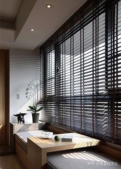 a living room filled with furniture and windows covered in blindes next to a plant