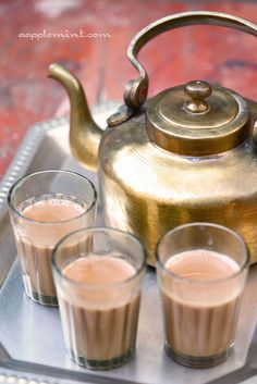 there is a tea pot and cups on the tray with drinks in front of it