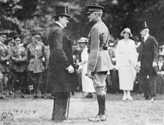 black and white photograph of two men standing next to each other in front of an audience