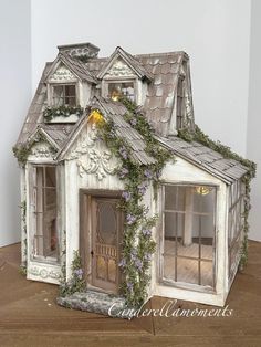 a doll house with ivy growing all over it's roof and windows on top of a wooden table