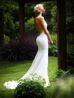 a woman in a wedding dress standing on the grass