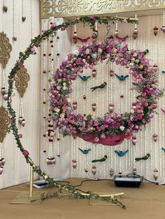 a pink and white floral wreath on display in front of a wall with beaded curtains