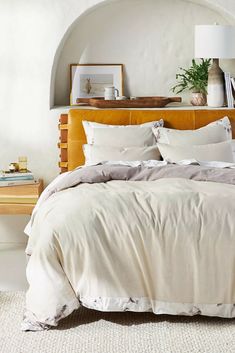 a bed with white sheets and pillows in a bedroom