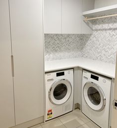 a washer and dryer in a small room with white cabinets on either side