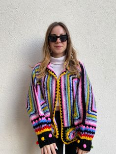 - Exquisite handcrafted crochet cardigan boasting vibrant hues of Blue, Purple, Pink, and Yellow. - Features a unique boho-chic design with playful pom-pom embellishments for a distinctive look. - Personalization options available for a cardigan that truly reflects your individuality. - Your satisfaction is key; enjoy precise craftsmanship with a promise of a 95% resemblance to the image. SIZES and MEASUREMENTS - The pictured item is suitable for sizes M. If you are unsure, please choose your regular size and give us your measurements! We'll make sure that the item is customized for you. PERSONALIZATION - Note that everything at Smyrna Collective is handmade individually by our creators. So we can do any Size / Design / Color customization that you like! Extra charge difference is applied Multicolor Granny Square Cardigan One Size, One Size Multicolor Granny Square Cardigan, One Size Multicolor Crochet Outerwear, Hand Knitted Multicolor Cardigan For Festivals, Hand Knitted Multicolor Festival Cardigan, Handmade Multicolor Cardigan For Festival, One Size Multicolor Crochet Sweater, Boho Chic Design, Multicolor Sweater