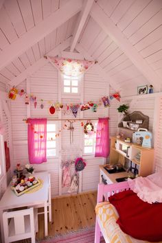 a room with white walls and pink curtains on the windows is decorated with hearts, buntings and other decorations