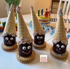 three chocolate covered cones with faces and sprinkles on them sitting on a table