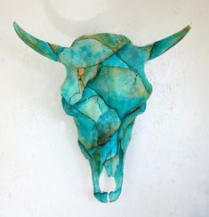 a bull's head made out of blue and green paint on a white wall