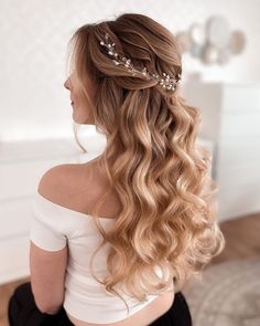 a woman with long blonde hair wearing a tiara and sitting on the floor in front of a white wall