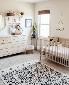 a baby's room with a crib, dresser and rug on the floor