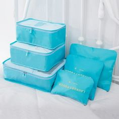 three blue suitcases sitting on top of a bed next to pillows and pillow cases