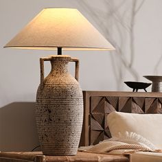 a lamp that is on top of a table next to a night stand and bed