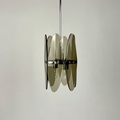 a modern light fixture with three circular mirrors hanging from it's center point, in an empty room