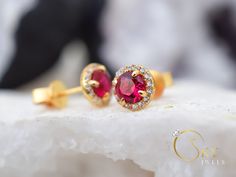 Gold ruby halo earrings, with a delicate yet eye capturing design. The stones have a stunning dark red color that gives you a mesmerizing effect with the accented stones all around. The Ruby is the birthstone of July. It represents love and passion. For centuries, this gem has been considered the king of all gems for its rarity, hardness (second only to a diamond), beauty and apparently mystical powers. Rubies have been the prized possession of emperors and kings throughout the ages, and to this Ruby Earrings With Halo Design For Wedding, Ruby Halo Design Earrings For Wedding, Red Halo Design Earrings For Wedding, Ruby Halo Earrings For Wedding, Wedding Ruby Earrings With Halo Design, Red Round Cluster Earrings For Wedding, Red Halo Setting Earrings For Wedding, Gold Ruby Earrings, Red Stud Earrings