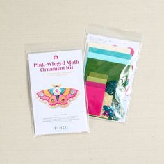 the pink winged moth ornament kit is in its package bag and next to it's packaging