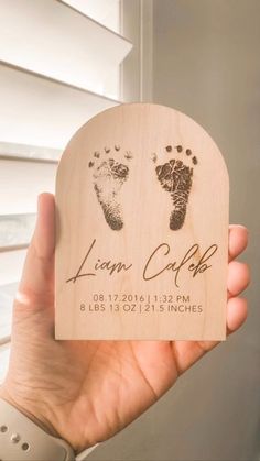 a person holding up a wooden plaque with footprints on it