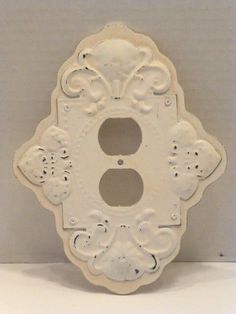 an old white light switch cover with ornate designs