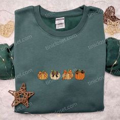 a green shirt with three pumpkins on the front and two small ones on the back