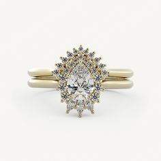 a yellow and white gold ring with an oval cut diamond surrounded by smaller round diamonds