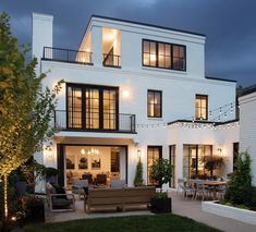 a large white house with lots of windows and lights on it's front porch