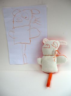 a stuffed animal is next to a drawing on the wall with an orange carrot in front of it