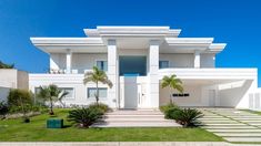 a large white house with palm trees in the front yard and stairs leading up to it