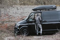 a man standing next to a van with a surfboard on top