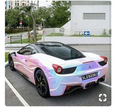 a pink and blue sports car parked in a parking lot next to a white building