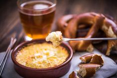 a spoon full of food next to a bowl of bread and a cup of tea