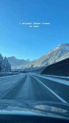 a car driving down a road with snow on the ground and mountains in the background