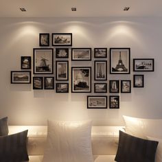 a living room filled with white couches and framed pictures on the wall above them