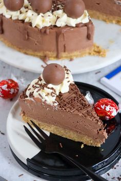 a slice of chocolate cake on a plate with a fork next to it and some candy in the background