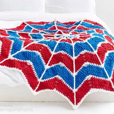 a red, white and blue crocheted blanket on top of a bed with pillows