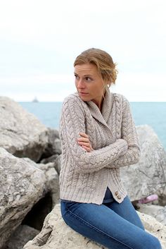 a woman is sitting on some rocks by the water