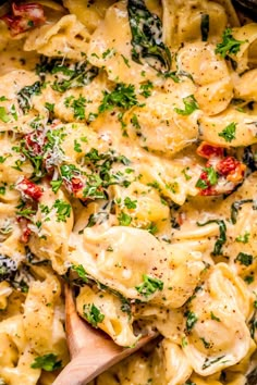 a skillet filled with pasta and spinach covered in cheese, sauce and parsley