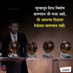 a man standing next to three golden soccer balls on display in front of an advertisement