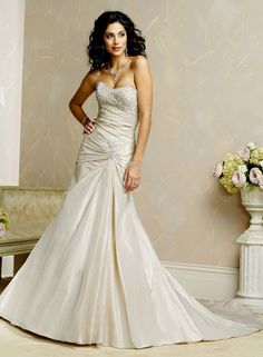 a woman in a wedding dress standing next to a vase with flowers on the floor