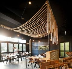 a restaurant with wooden tables and chairs in the middle, hanging from the ceiling above